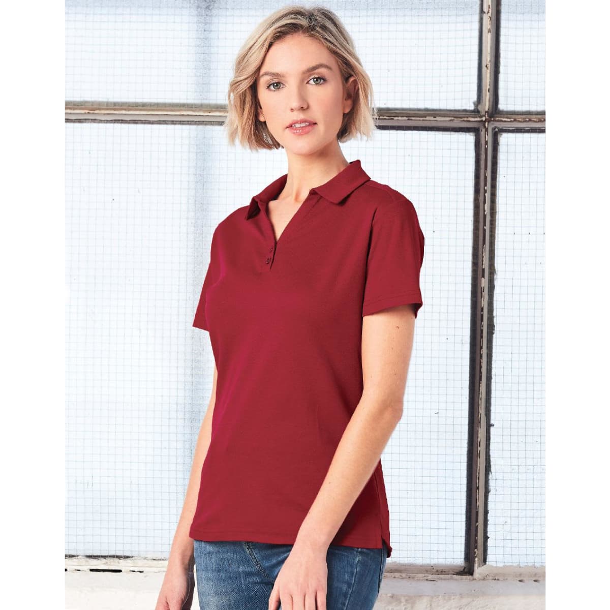 A woman wearing a burgundy short sleeve polo shirt with a collar. The shirt features a logo.