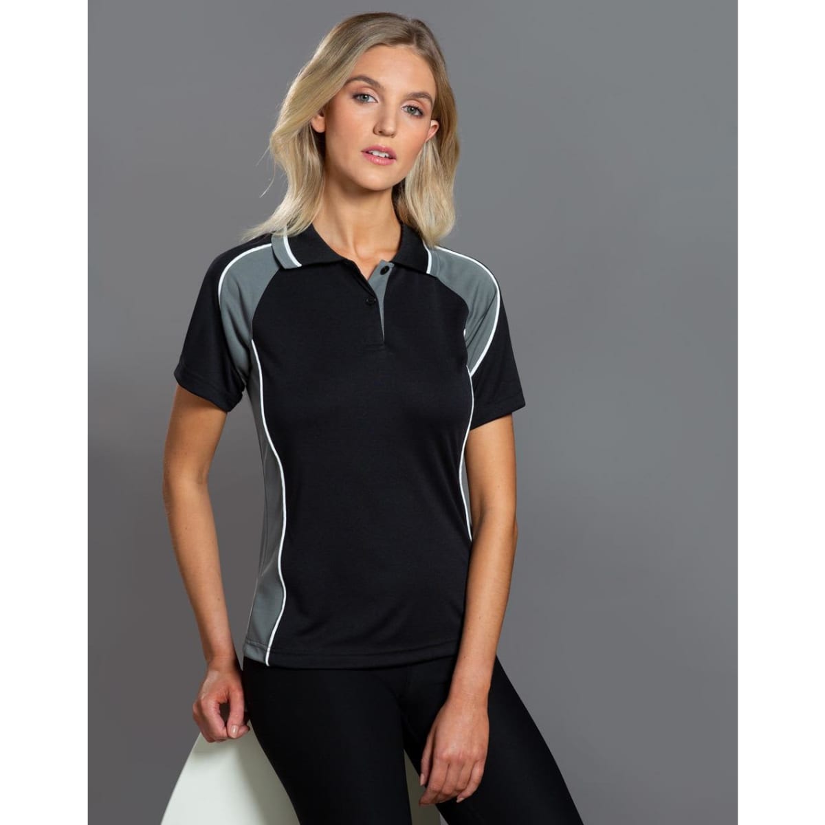 A black and grey Ladies' Mascot Polo shirt with a logo, featuring contrasting side panels and a collar.