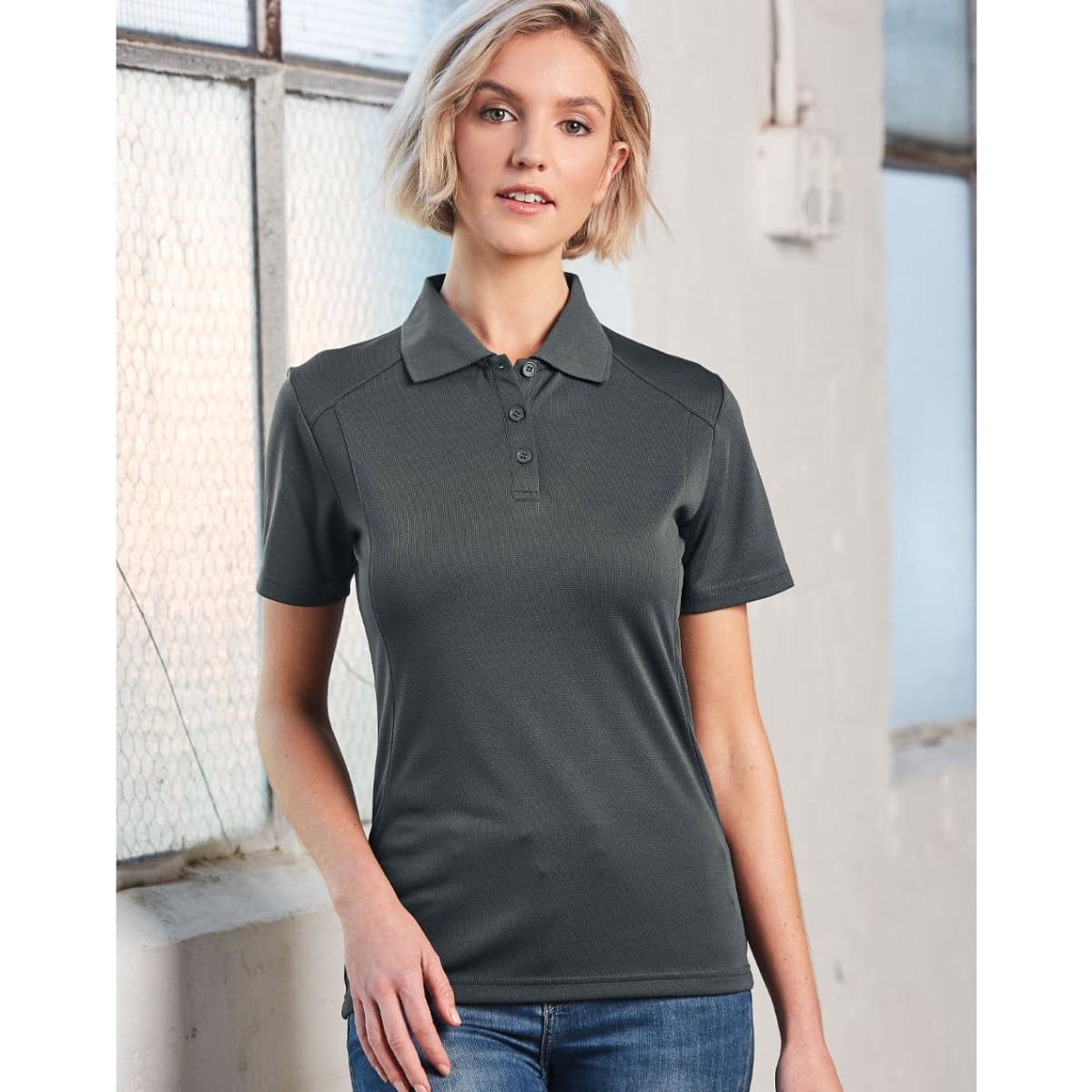 A grey polo shirt for ladies with a collared neckline and buttons, featuring a logo on the chest.