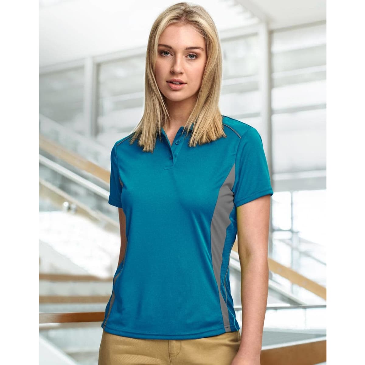 A teal women's polo shirt with grey contrast panels and a three-button placket, featuring a logo.