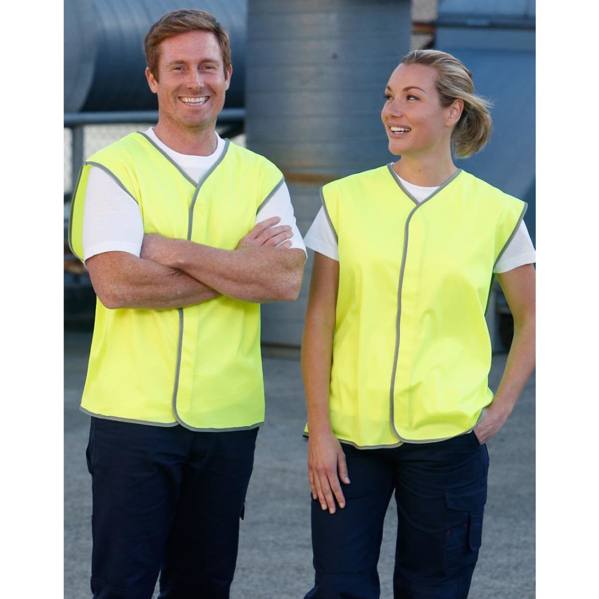 A hi-vis safety vest in bright yellow, worn by two smiling individuals. The vests feature a grey trim and have a logo.