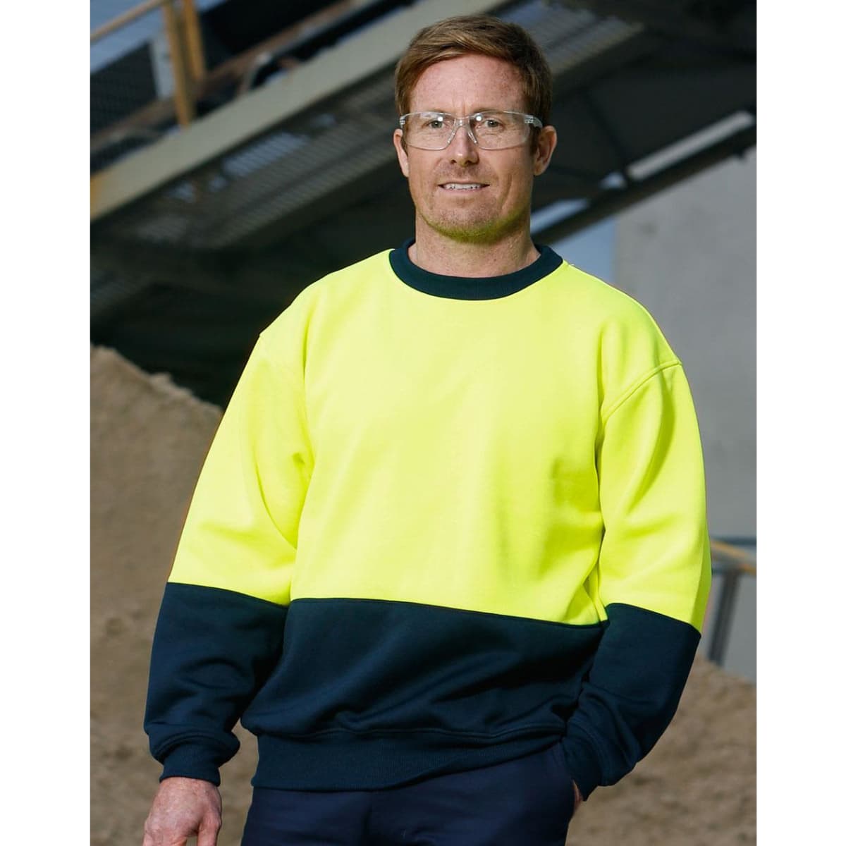 A Hi-Vis two tone safety windcheater in bright yellow and navy, worn by a man with safety glasses.