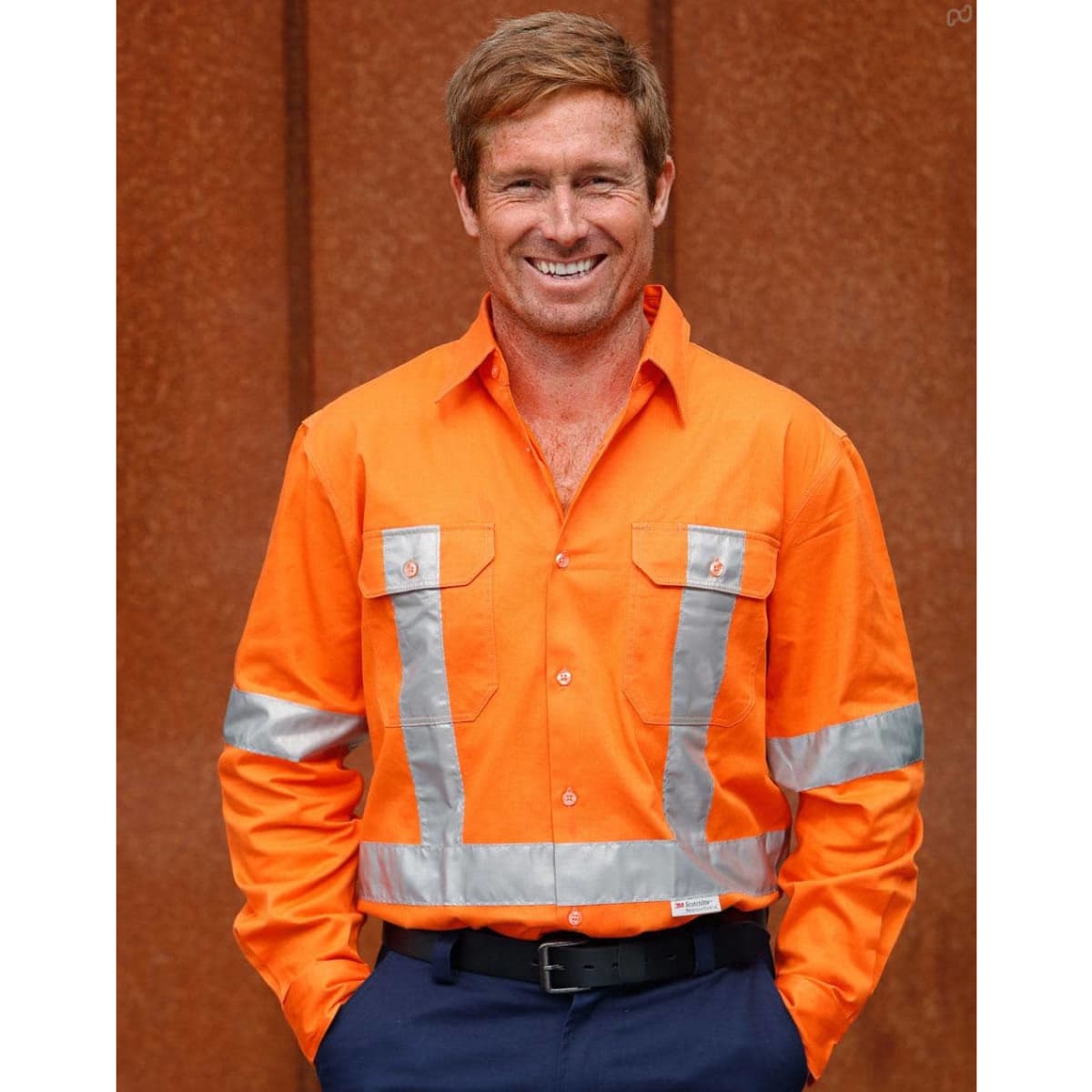 A bright orange long-sleeve drill shirt with reflective 3M tape and two chest pockets. The shirt features a logo.