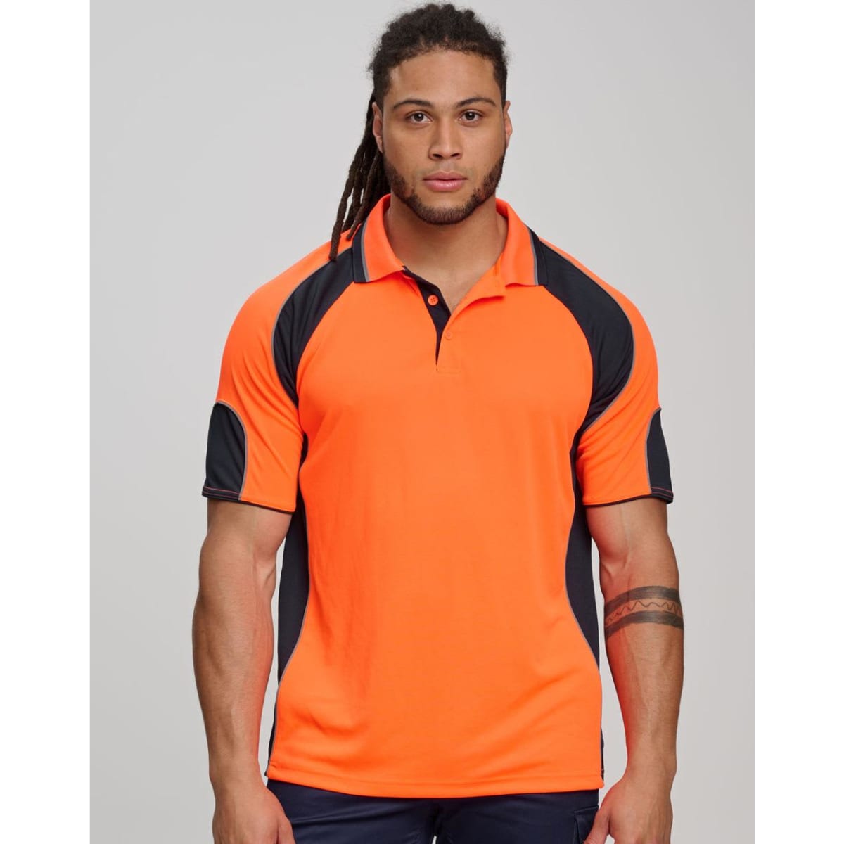 Men and woman in high-visibility orange polo shirts with navy sleeves, standing in a construction setting. 