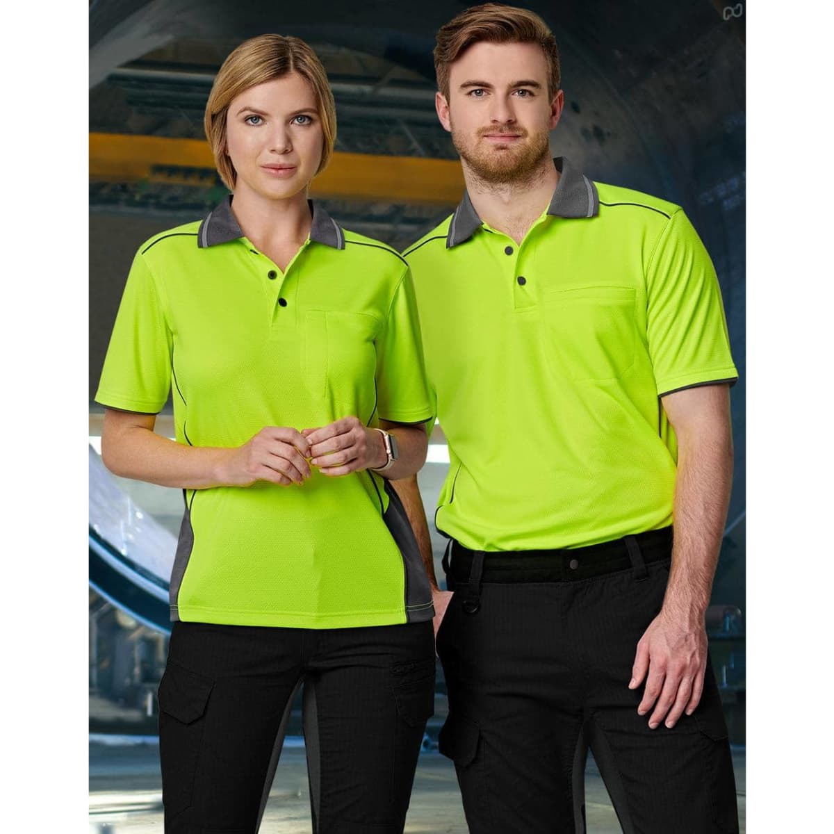 A vibrant hi-vis yellow polo shirt with grey accents, featuring a pocket, modelled by a male and female duo.