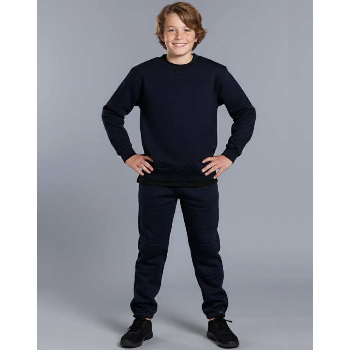 Kid's black fleecy trackpants with zip, cuffs, knee padding, and pockets, featuring a logo.
