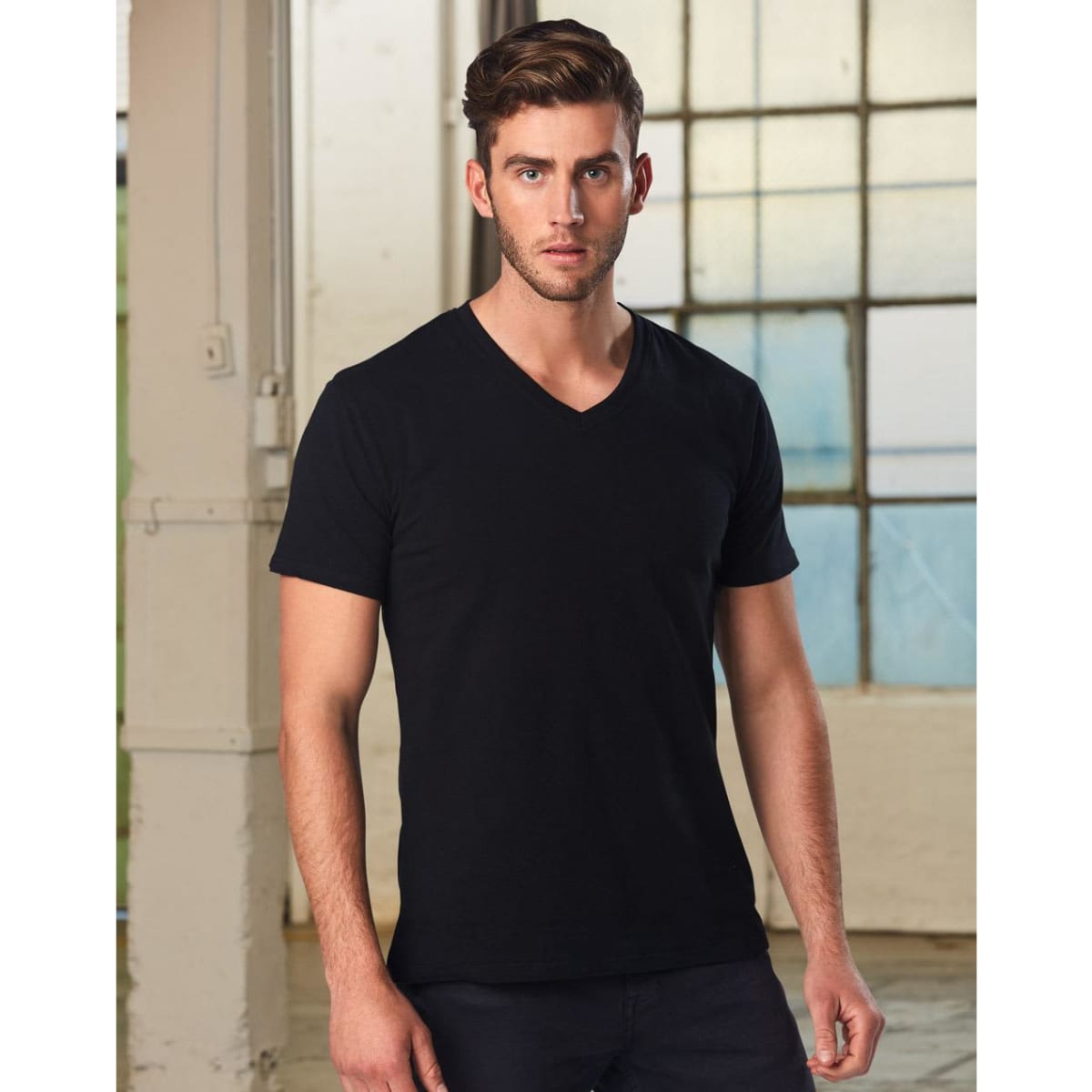 A men's black V-neck short sleeve tee, displayed on a model with a neutral background and natural lighting.
