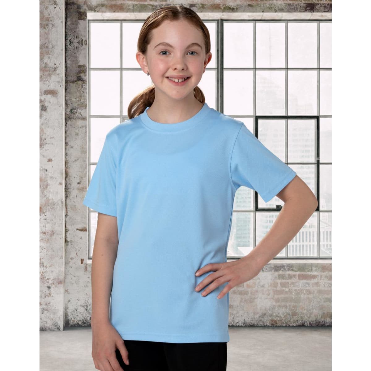 A light blue kids' short sleeve tee, featuring a simple design and a logo on the front, displayed on a girl.