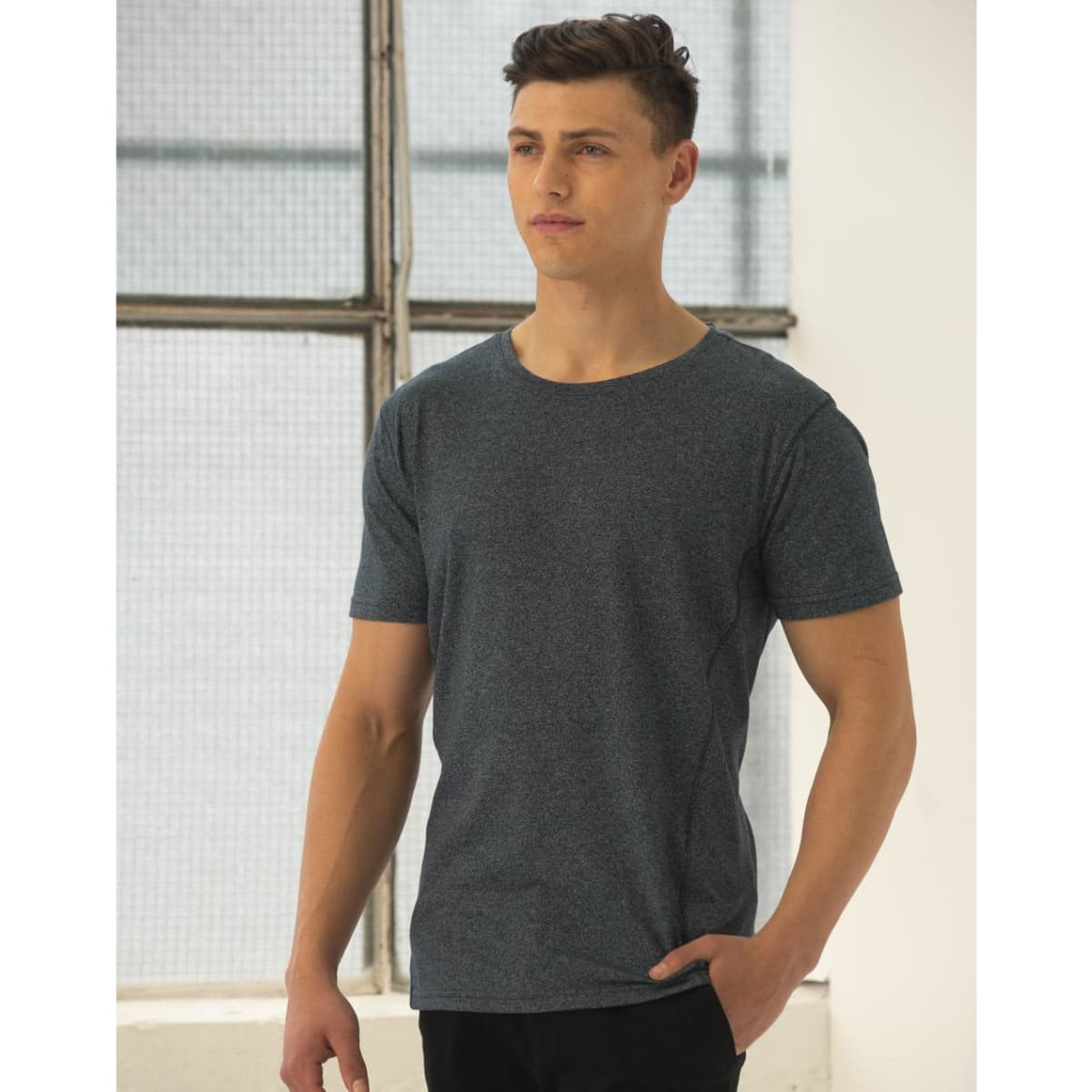 A model wearing a blue heather short-sleeve t-shirt with a relaxed fit, featuring a visible logo.