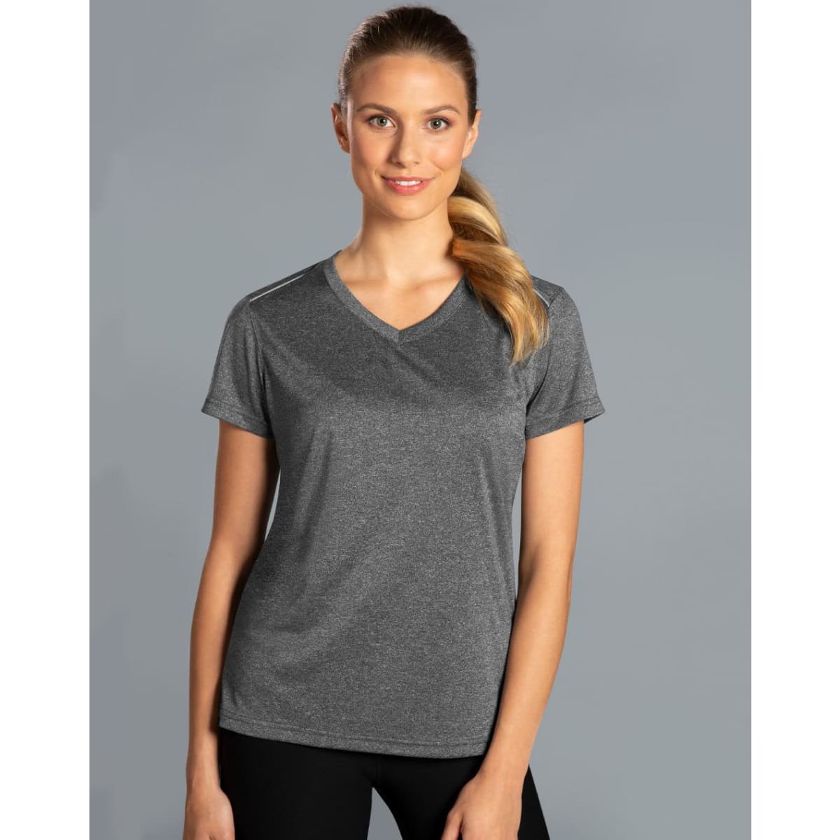 A grey short sleeve tee with a V-neck design, featuring a logo, worn by a smiling woman against a plain background.
