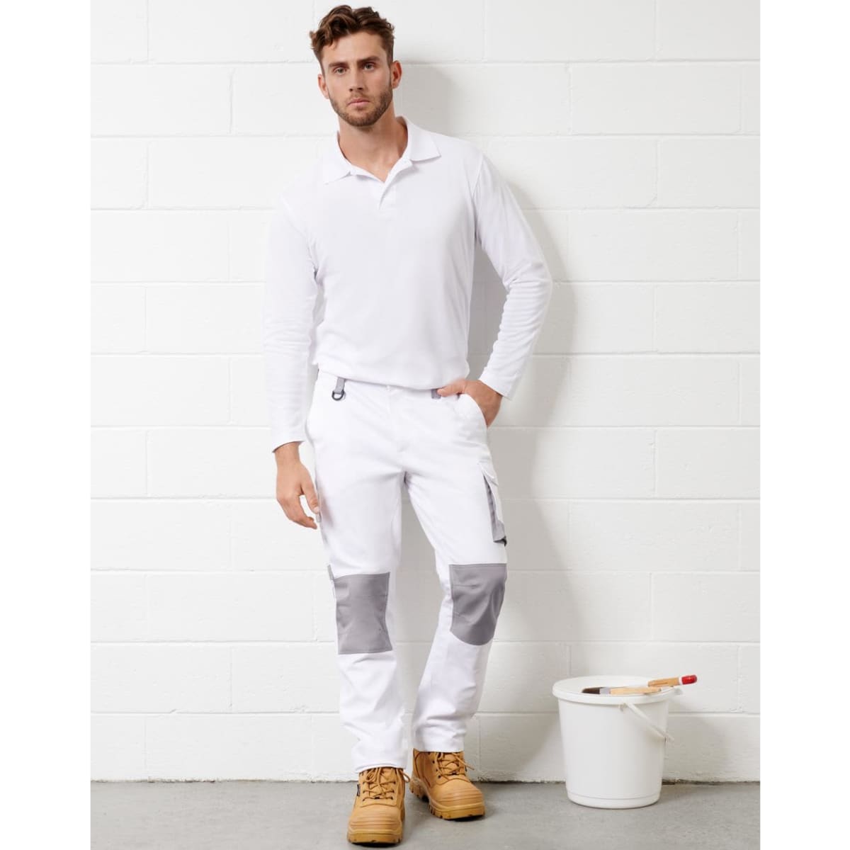 Unisex utility stretch cargo work pants in white with grey accents, featuring pockets. Model wearing a long-sleeve white shirt.