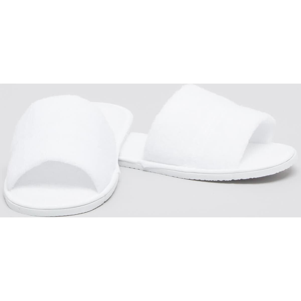 White open-toe spa bathroom slippers with a fluffy texture and flat soles, presented on a plain background.