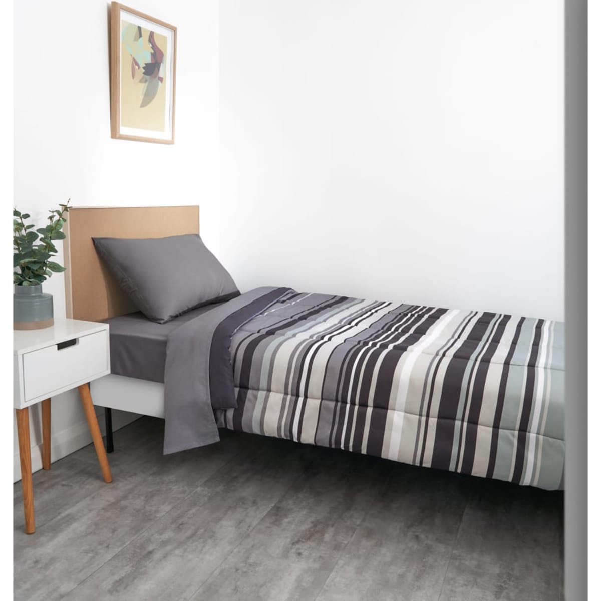 A striped charcoal comforter is neatly spread on a single bed with grey and black accents, accompanied by a decorative pillow.