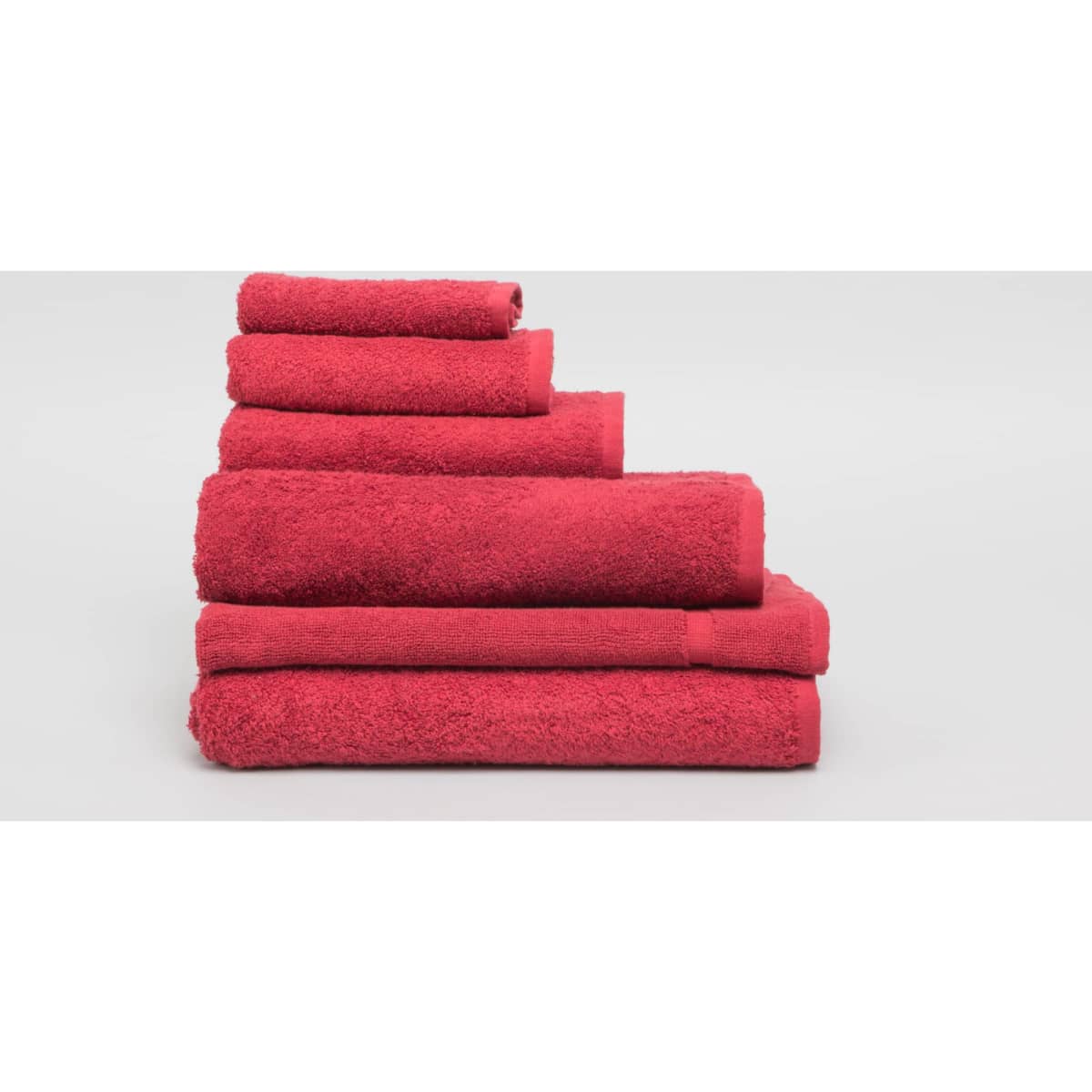 A collection of burgundy bath towels stacked neatly, showcasing various sizes and a soft, textured appearance.