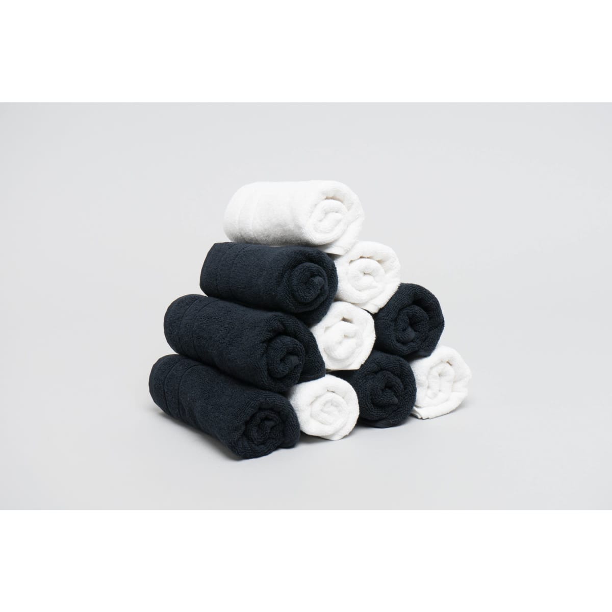 A stack of rolled towels in black and white, arranged in a pyramid shape against a light background.