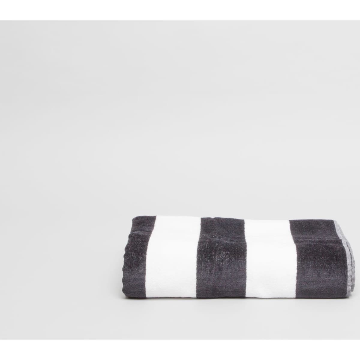 A folded towel featuring black and white stripes, showcasing a soft texture. Includes a logo.