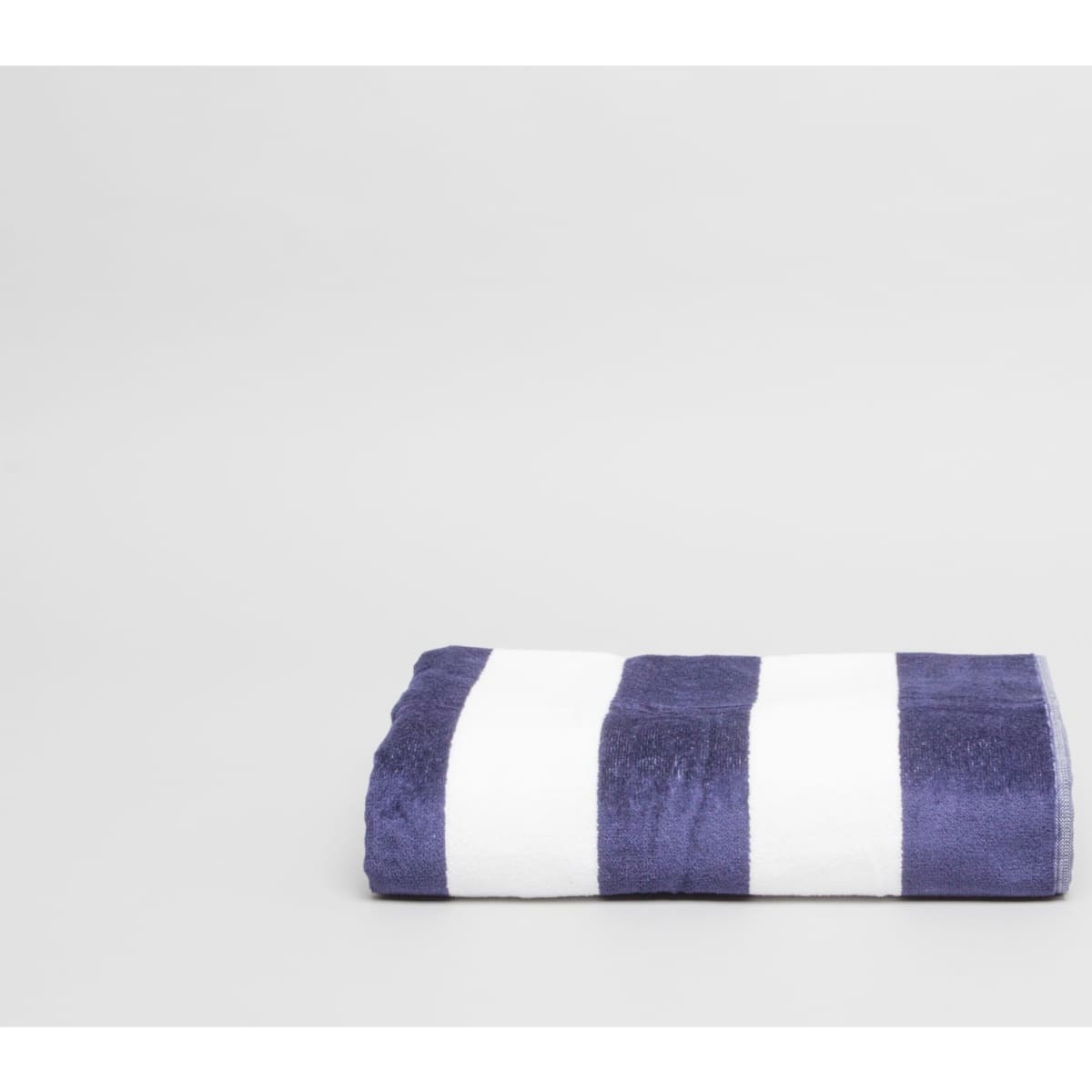 A folded beach towel featuring navy blue and white stripes, made of 450 gsm fabric. It has a logo on it.