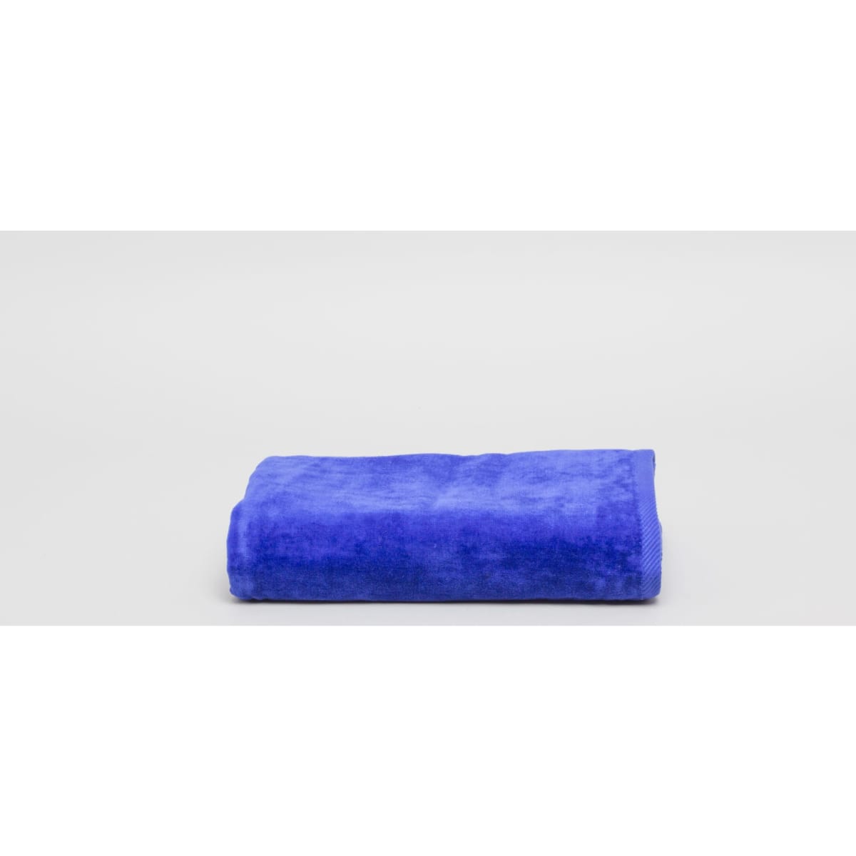 A folded royal blue beach pool towel with a soft, plush texture. It features a branding logo.