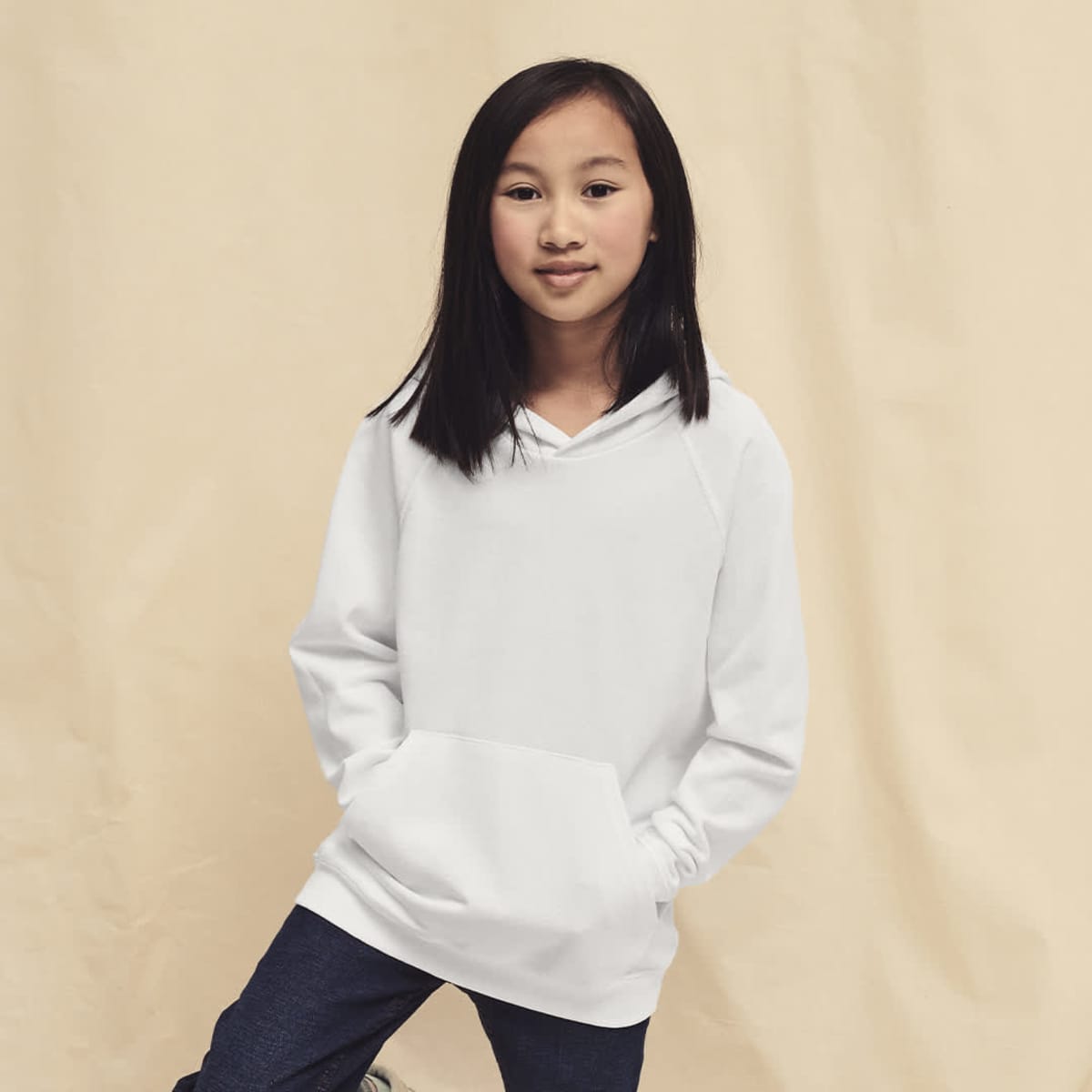 A lightweight hooded sweatshirt in white, featuring a front pocket and a relaxed fit, modeled by a young girl.