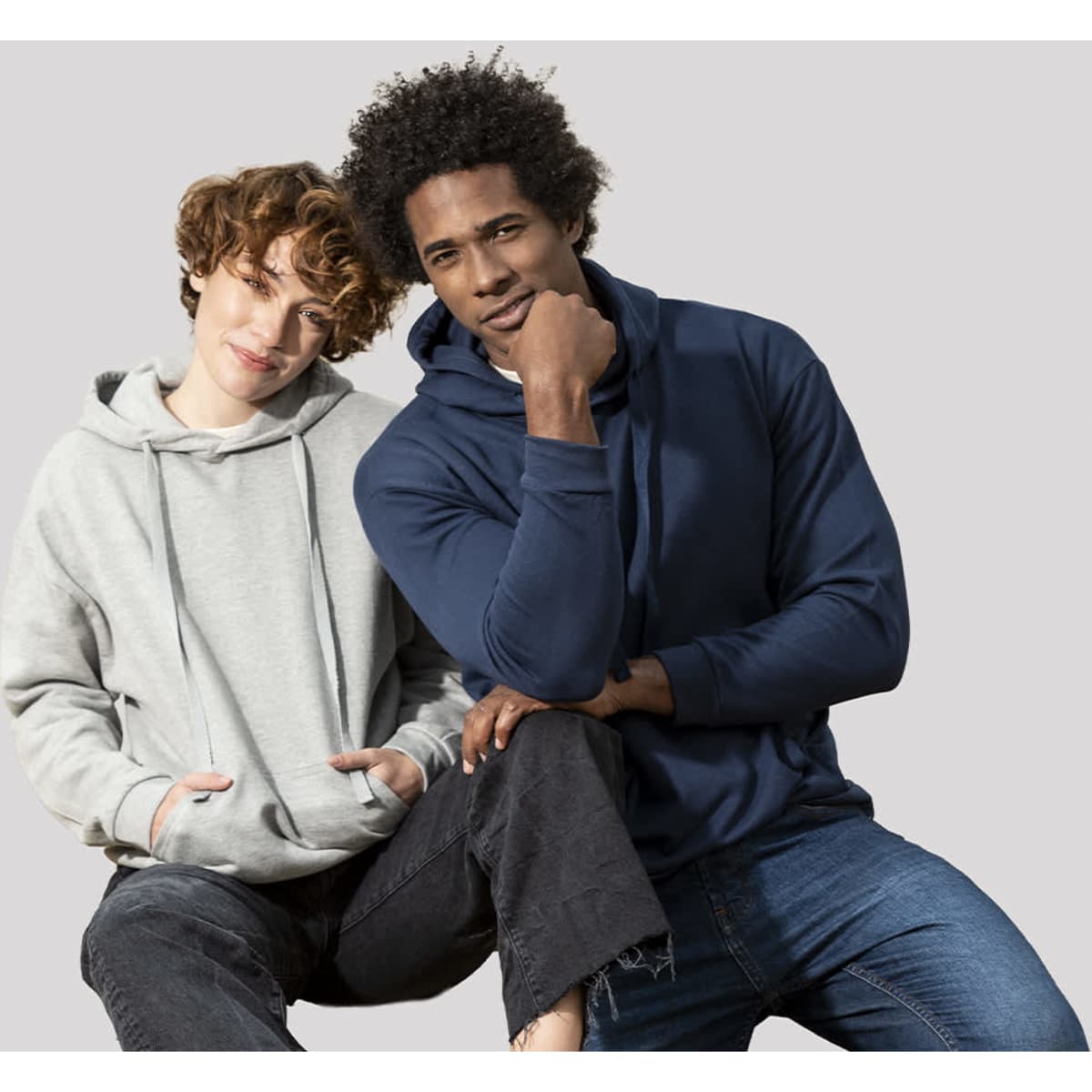 A grey hoodie and a navy hoodie worn by a man and a woman, both smiling while sitting together.