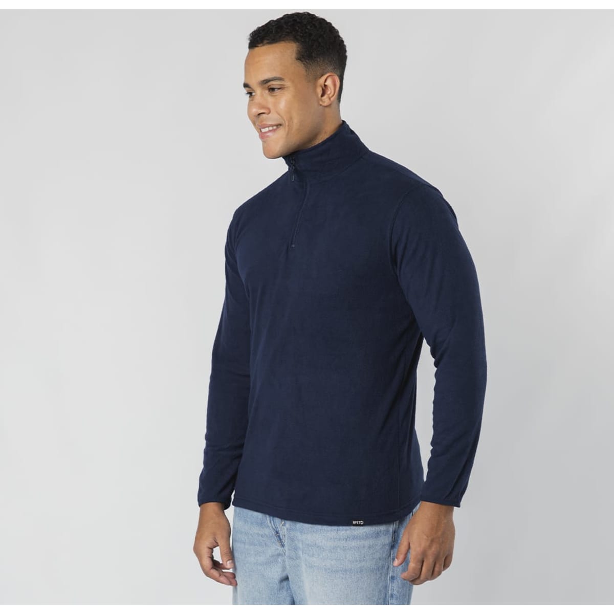 A navy blue polar fleece jacket with a high collar and a zip, worn by a smiling man. It features a logo.