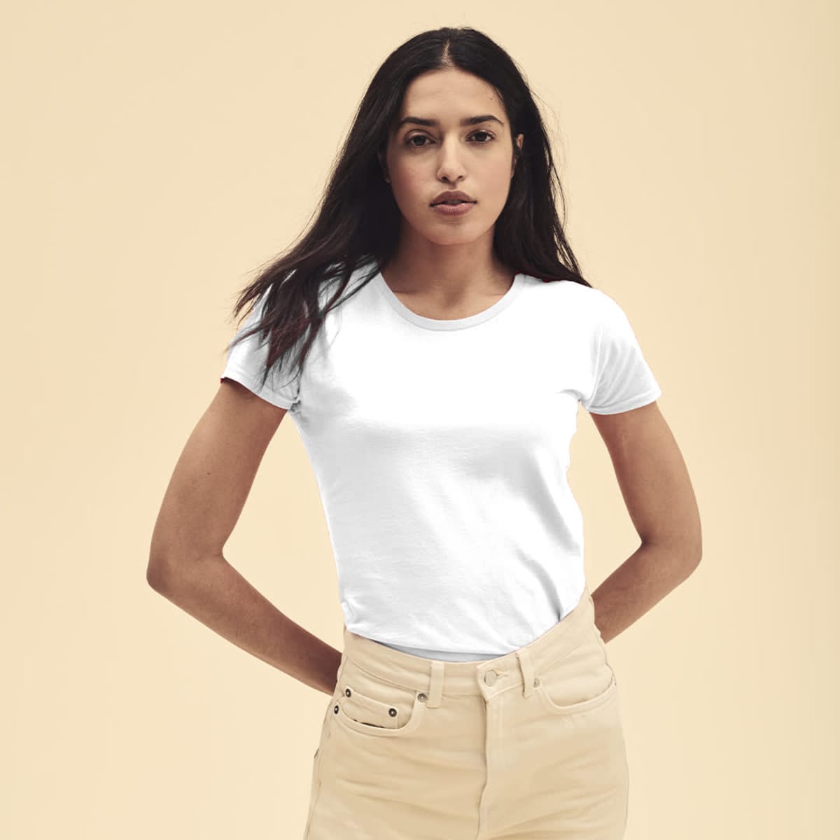 A fitted white t-shirt displayed on a model, paired with light-coloured trousers, against a neutral background.