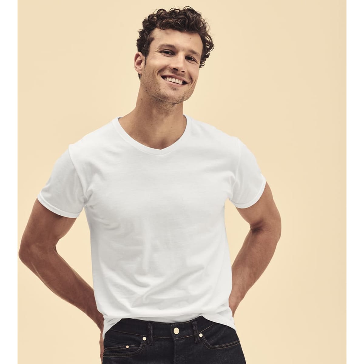A white V-neck T-shirt featured on a smiling male model, paired with dark jeans, and set against a neutral background.