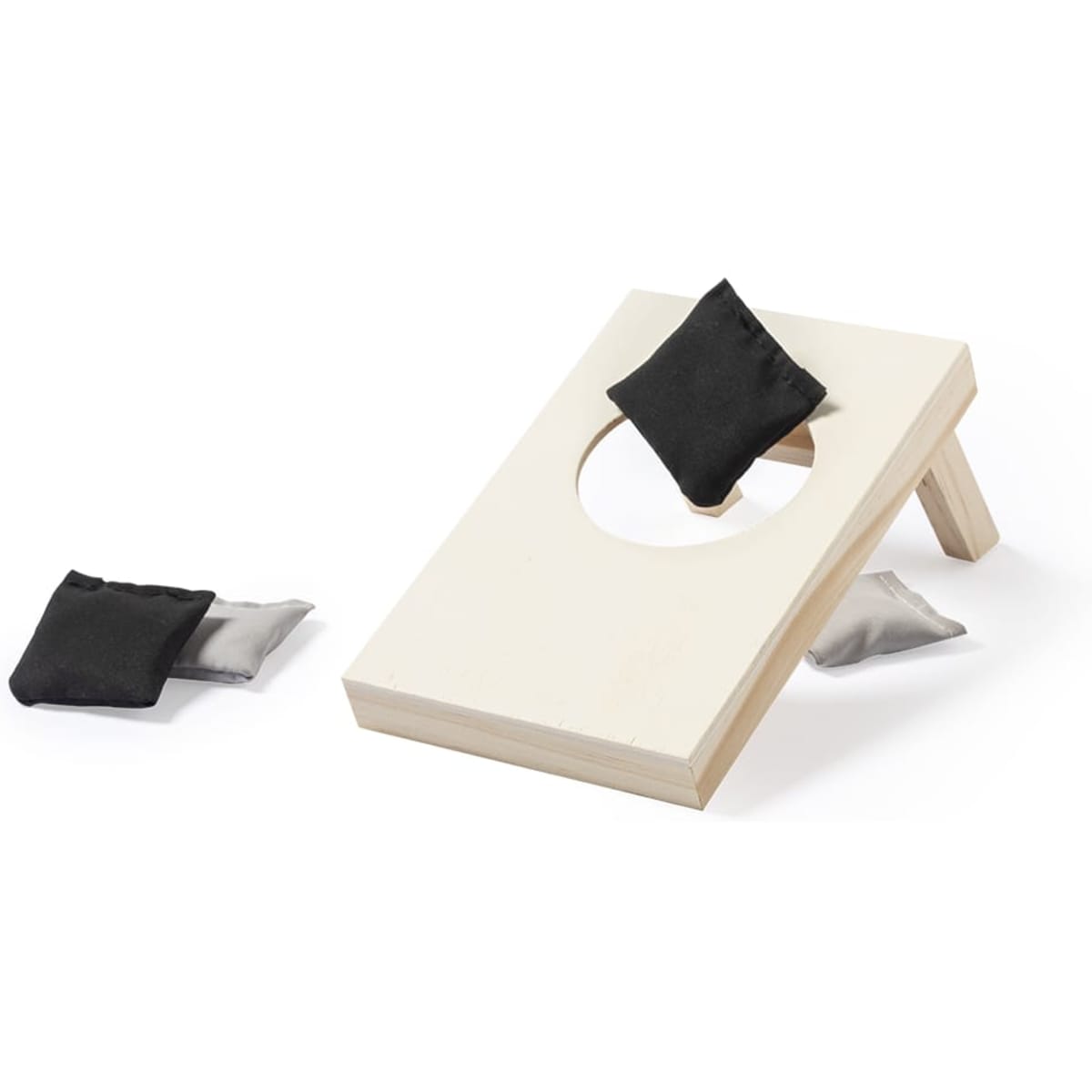 A wooden bean bag toss game in light colour with two dark fabric bags nearby. The game features a circular hole for scoring.