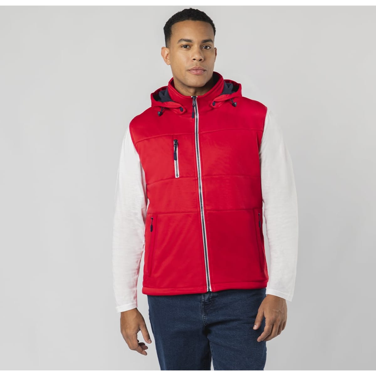 A red vest with a hood, featuring zippers and a front pocket, worn by a model. It has a logo on the chest.