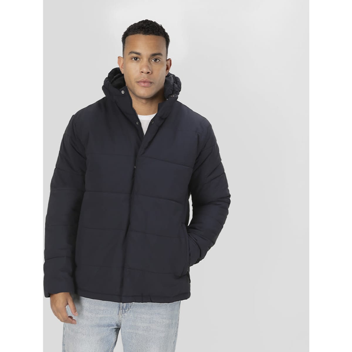 A dark navy rain jacket with a hood displayed on a model, featuring a puffer design and a logo.