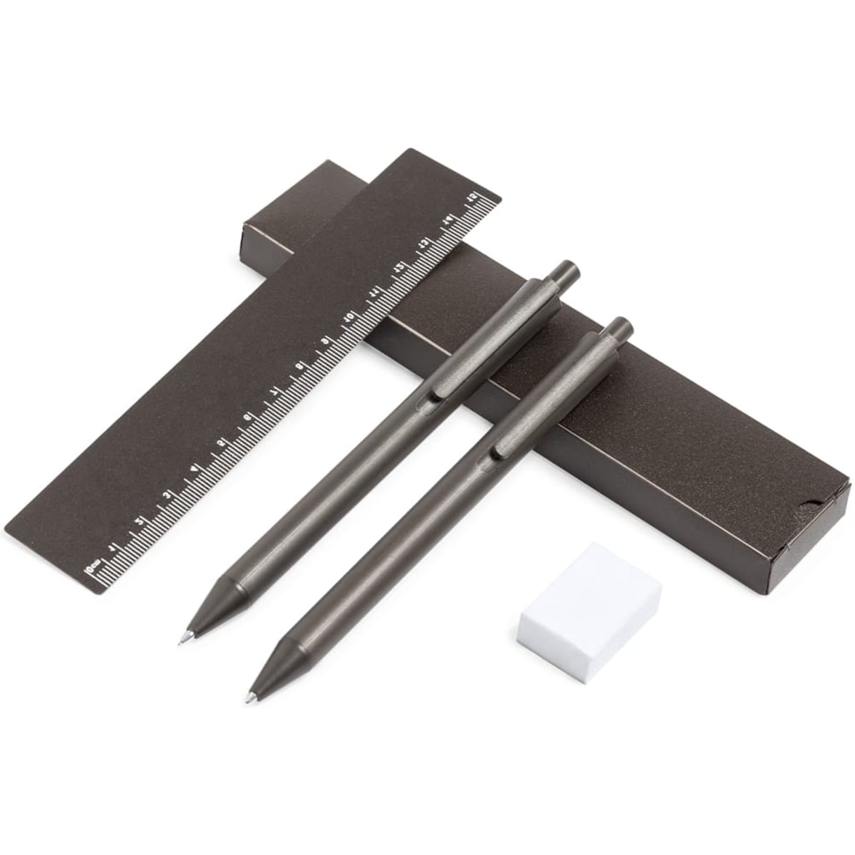 A dark grey gift set featuring two pens, a ruler with measurements, and an eraser, all packaged together.