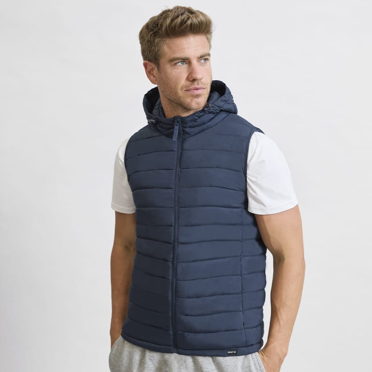 A navy puffer vest with a hood, featuring horizontal stitching and a zip closure, displayed on a model.