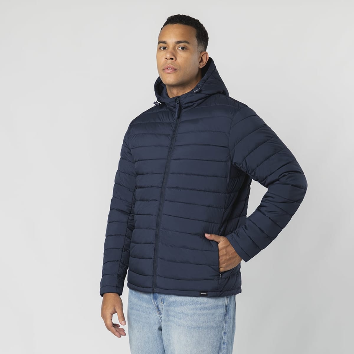A puffer jacket in navy blue featuring a zip-up front and a hood, displayed by a model.