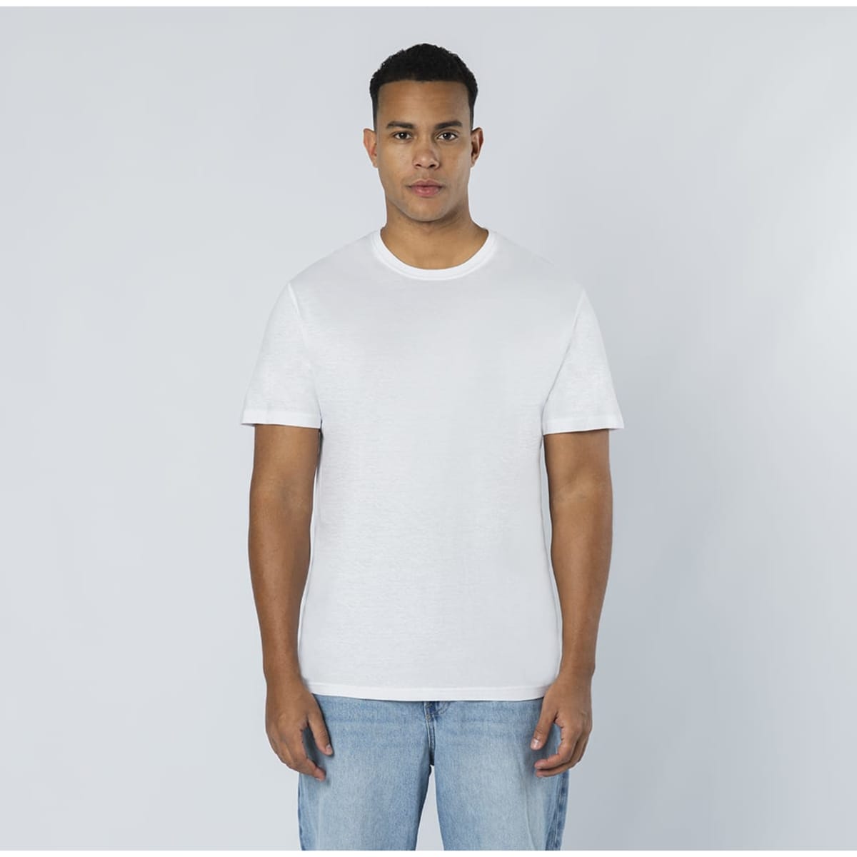A white T-shirt displayed on a model, paired with blue jeans. The shirt features a logo.