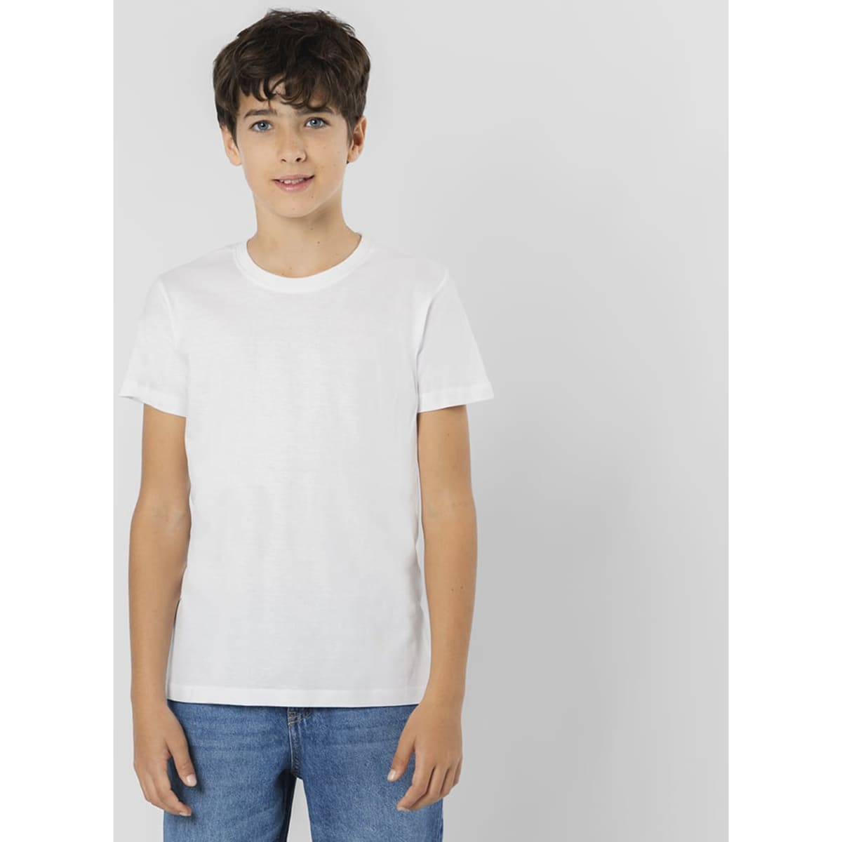A white t-shirt on a young model, paired with blue jeans, featuring a simple design and a brand logo.