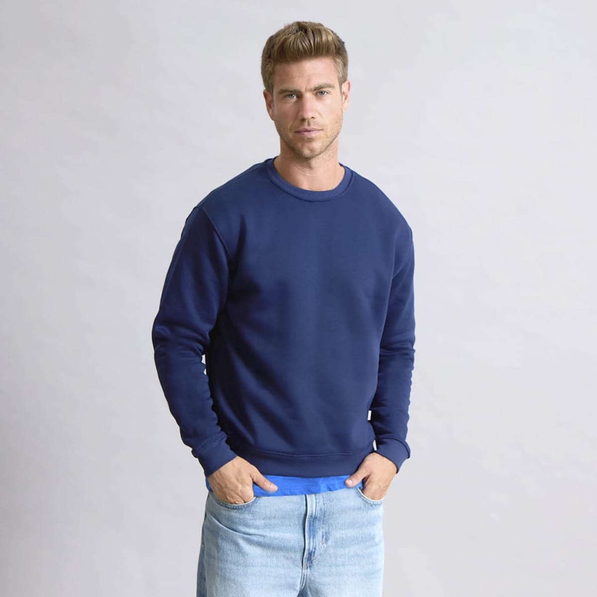 A navy blue hoodie worn by a model, featuring a round neckline and long sleeves. The model stands against a neutral background.