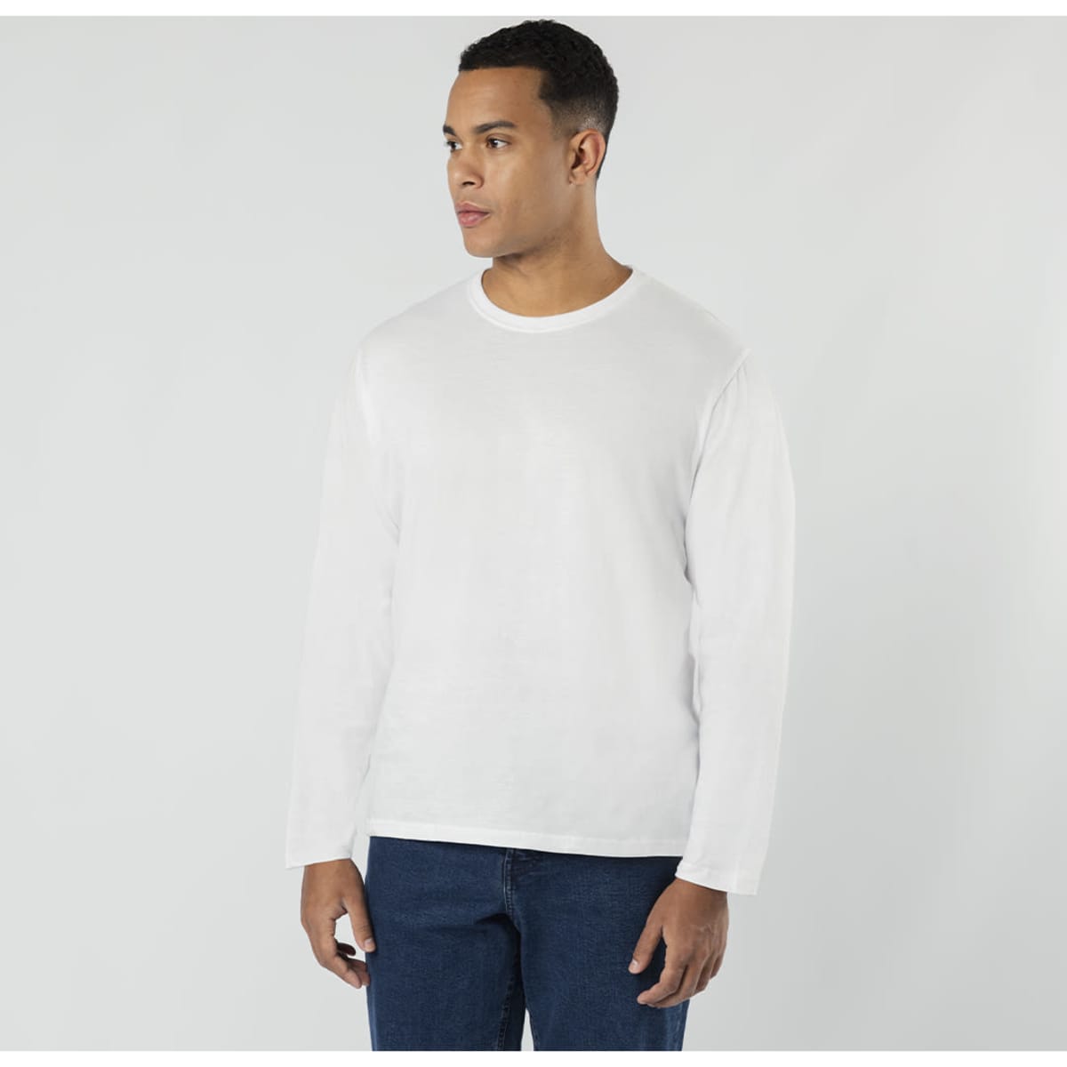 A white long-sleeve T-shirt displayed on a model, paired with blue jeans. The shirt features a small logo.