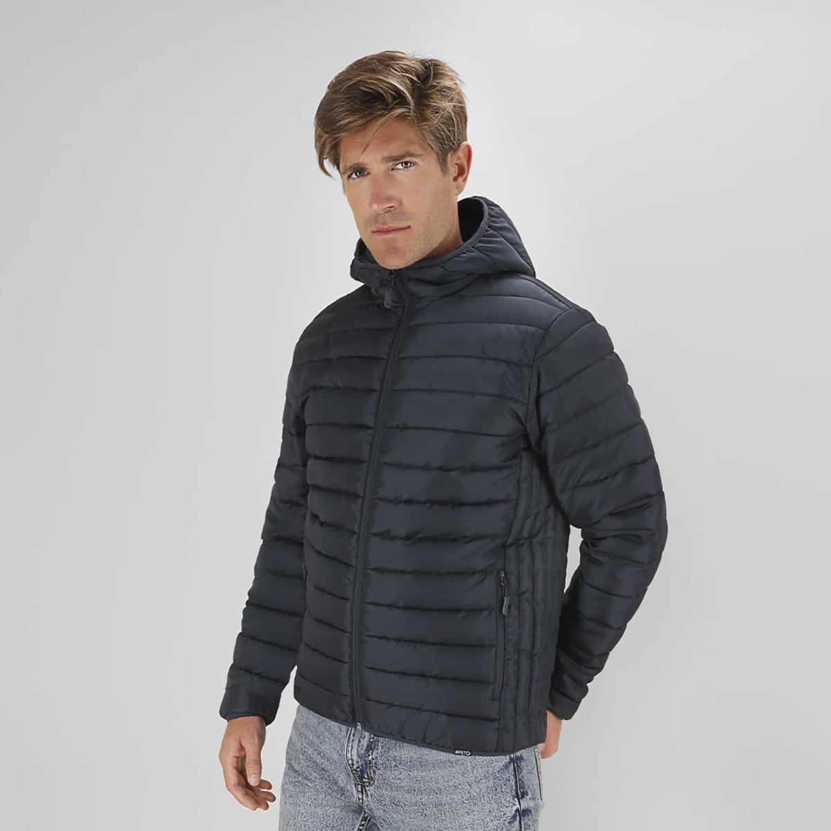 A navy Dilax Jacket featuring a hood and quilted design, displayed by a man in a neutral background.