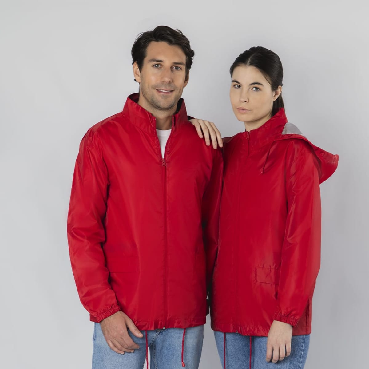 A red rain jacket featuring a zip-up front and hood, worn by two models against a grey background.