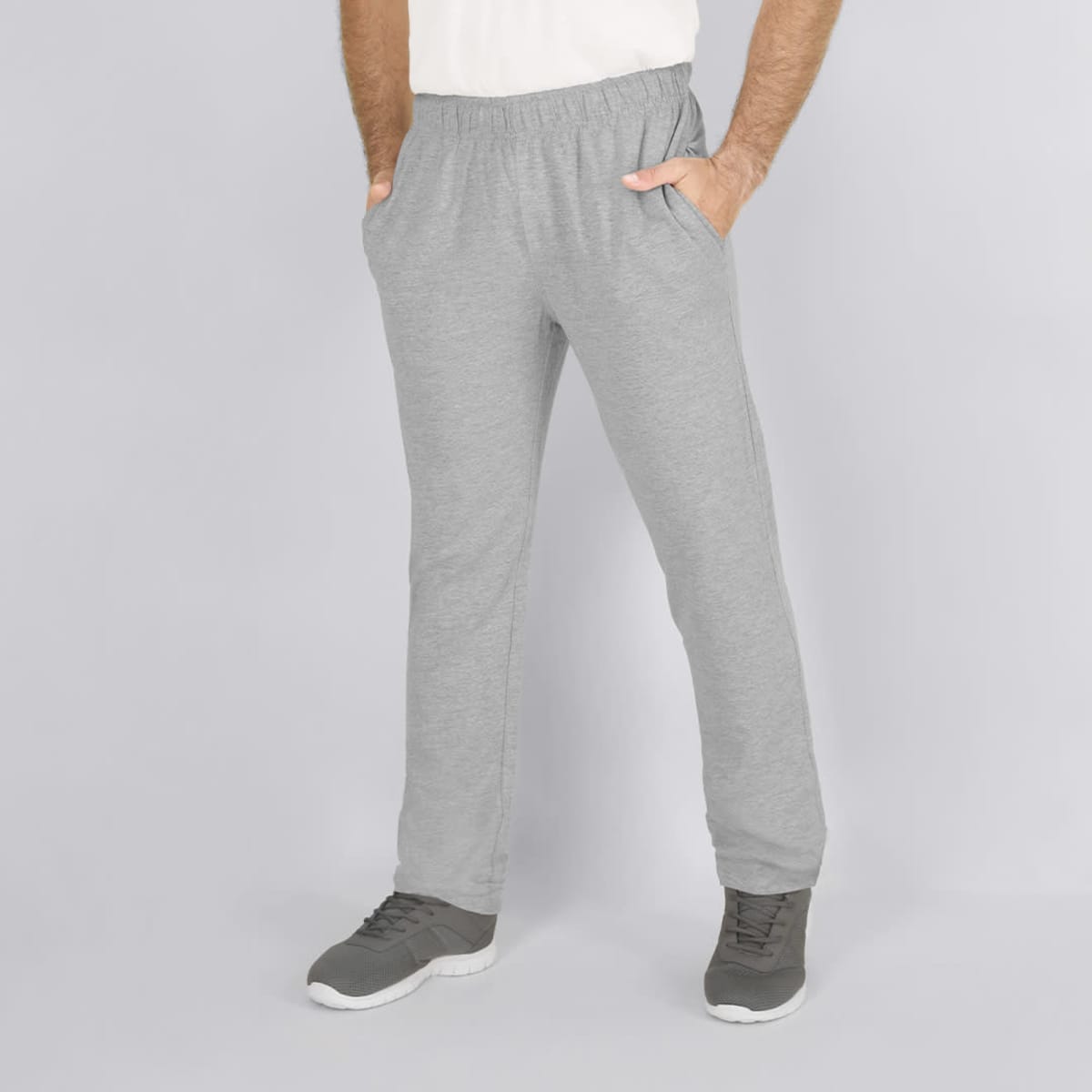 Light grey track pants with pockets, shown being worn by a person, paired with grey shoes.