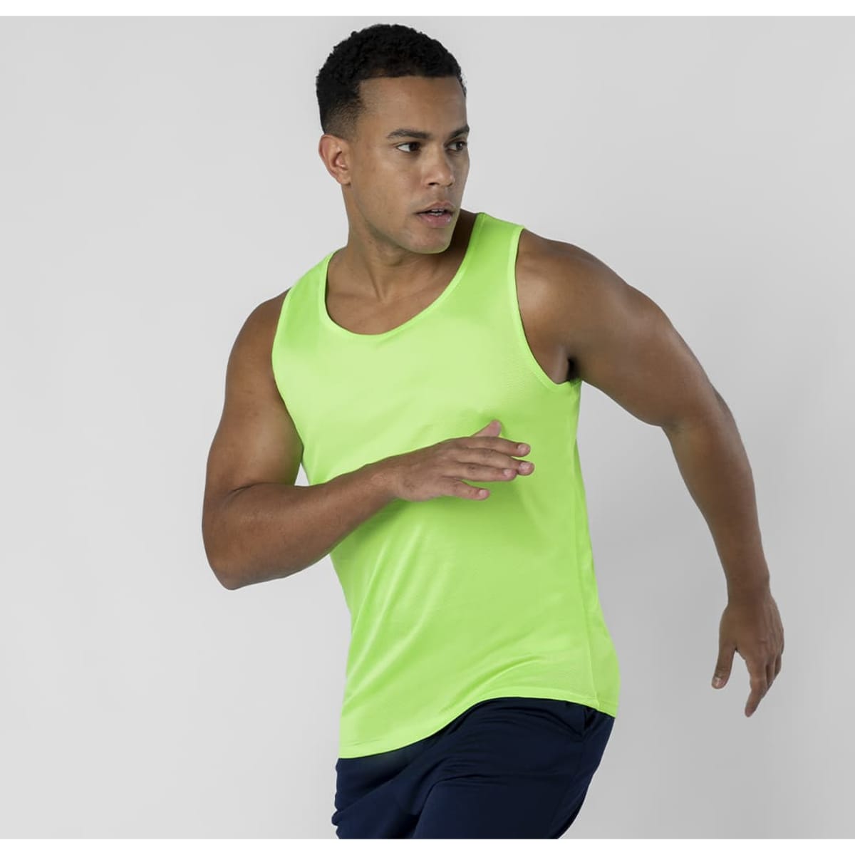 A bright green tank top worn by a man in motion, showcasing a sporty design. The garment has a logo on it.