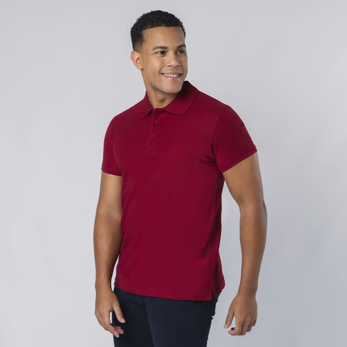 A red polo shirt with a collar, short sleeves, and a side slit, worn by a smiling model. It features a logo.