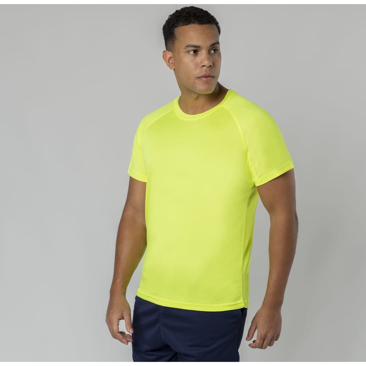 A bright yellow T-shirt worn by a man, featuring short sleeves and a round neckline, alongside dark blue shorts.