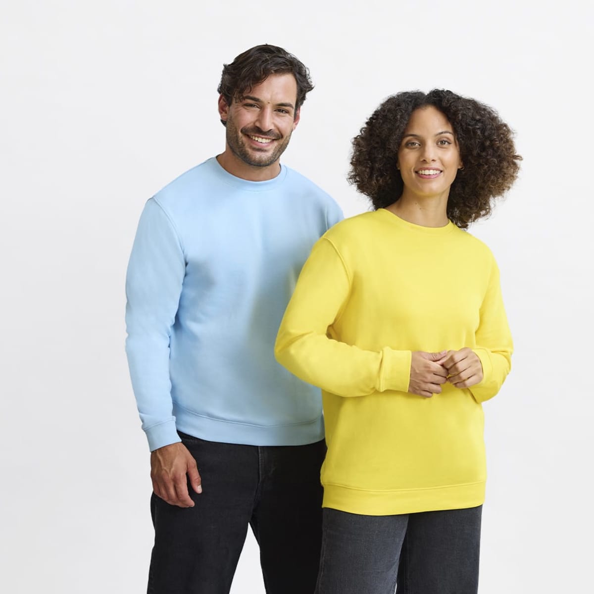 A blue hoodie worn by a man and a yellow hoodie worn by a woman, both smiling. The hoodies have branding on them.