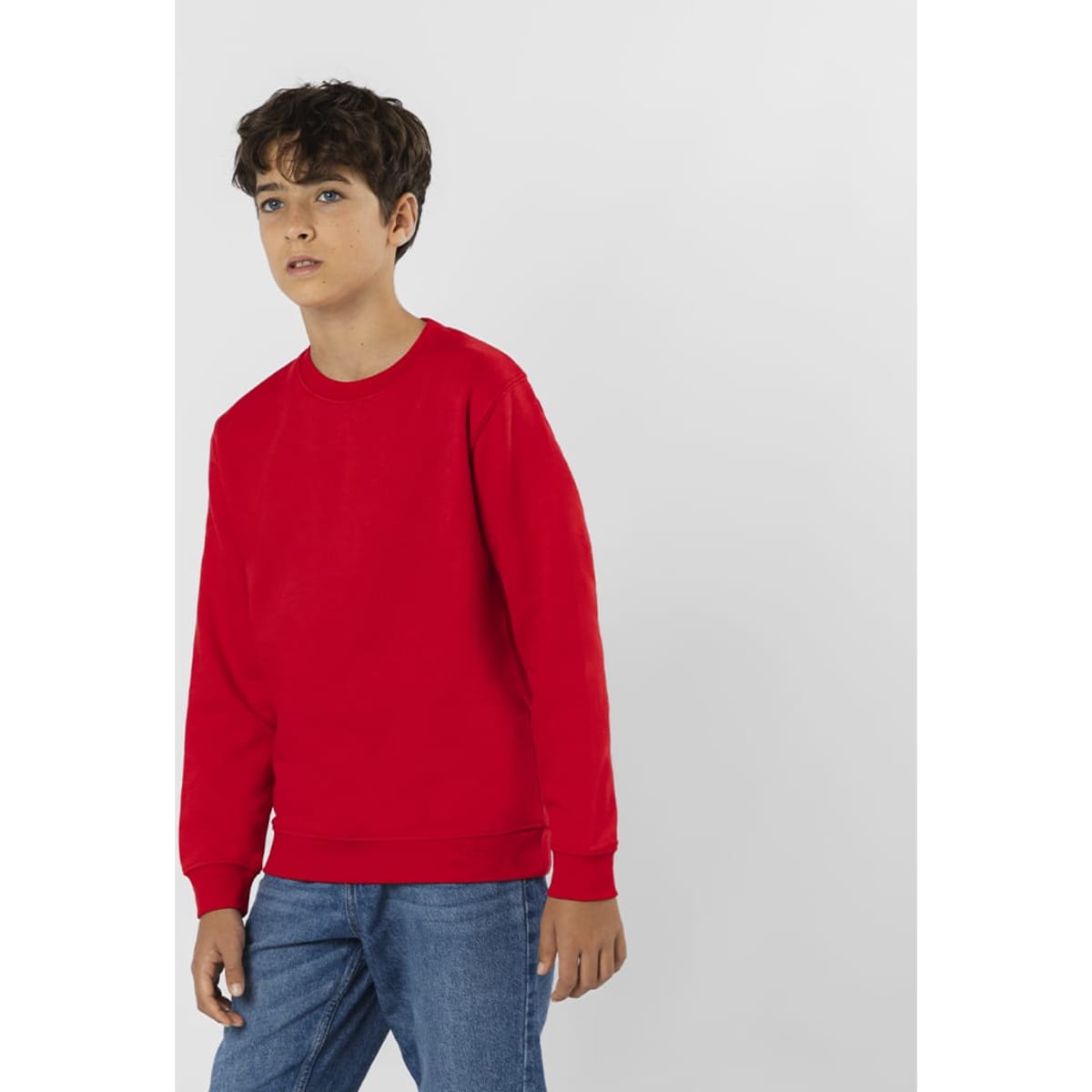 A red sweater with a crew neck design, featuring long sleeves and a plain style, worn by a boy.