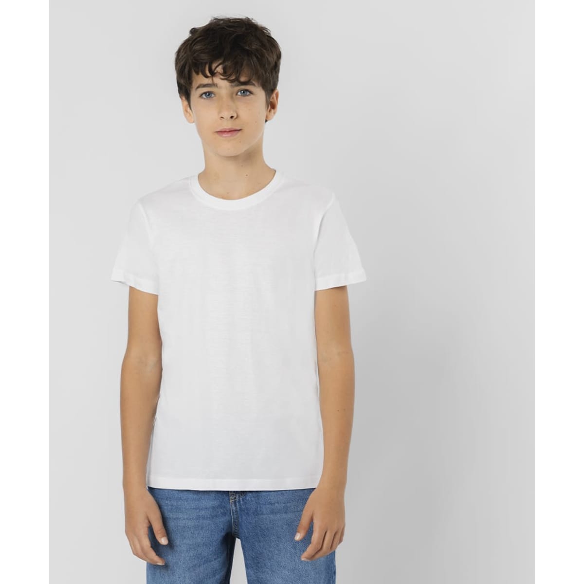 A white t-shirt displayed on a young model, paired with blue jeans. It features a simple design and has a logo.