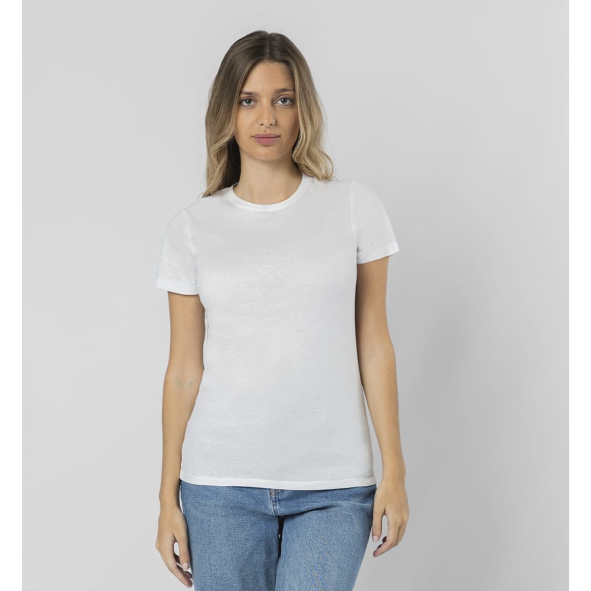 A white T-shirt with a fitted design displayed by a model in casual blue jeans. The T-shirt features a logo.