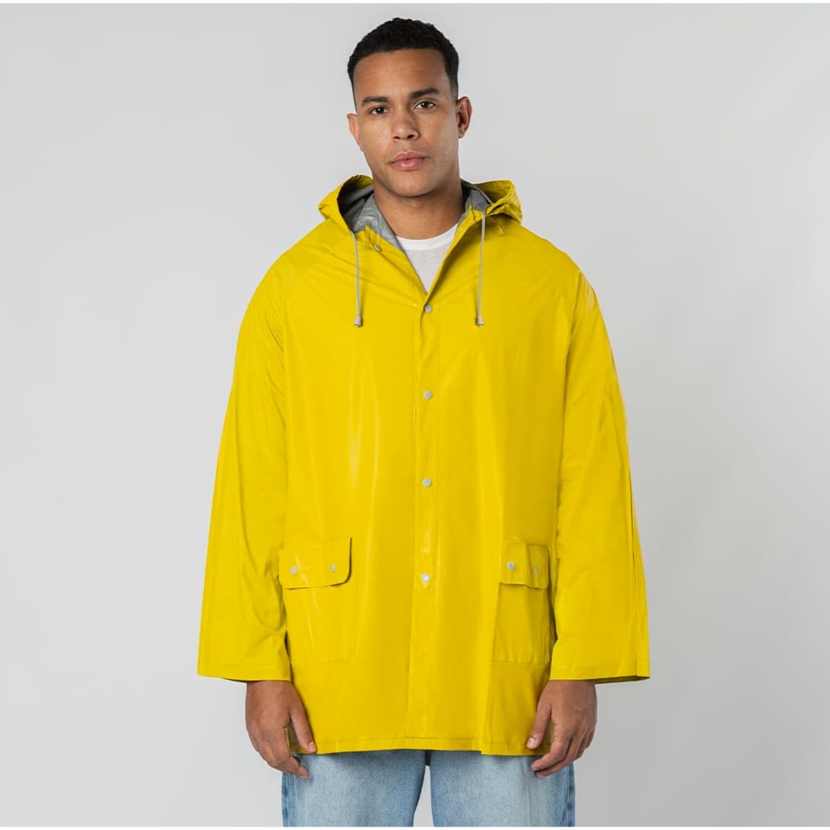 A man wearing a bright yellow rain jacket with a hood, featuring pockets and a grey lining.