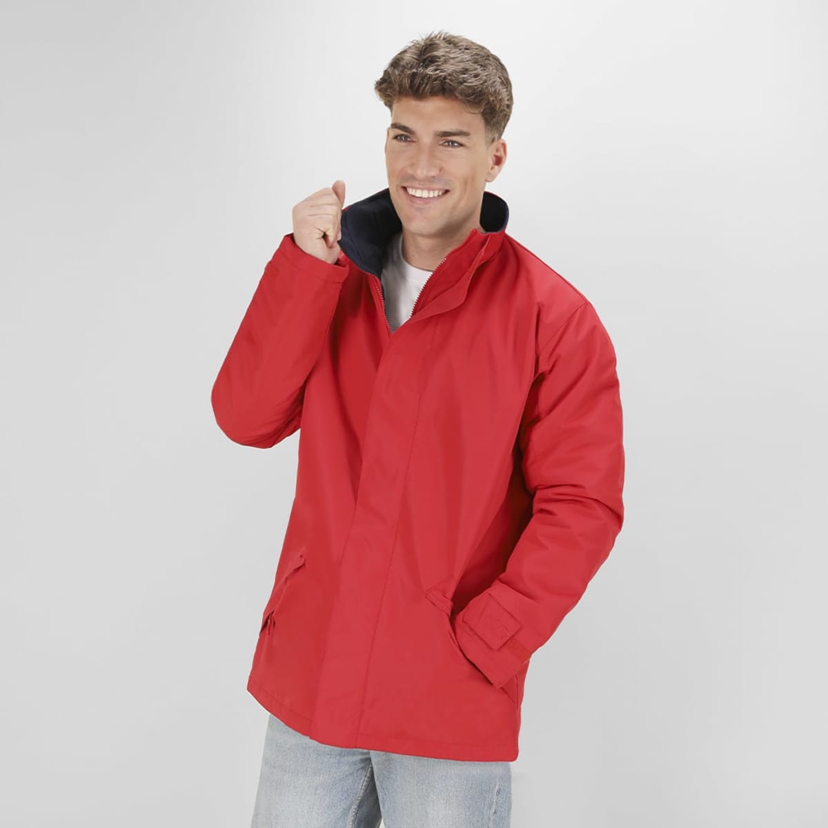 A red puffer jacket with a high collar and black lining, modelled by a smiling young man.