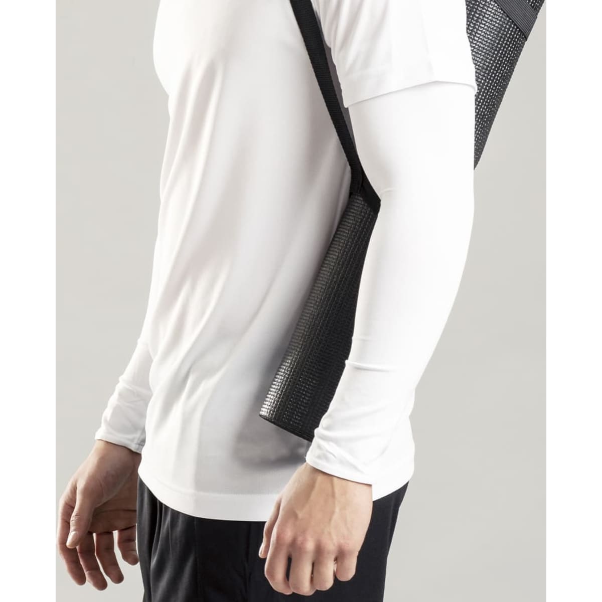 A person wearing a white long-sleeve shirt, carrying a black mesh tote bag over their shoulder.